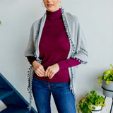 Model Wearing Alpine Cashmere Pom-Pom Triangle Wrap in Birch and Flannel Gray