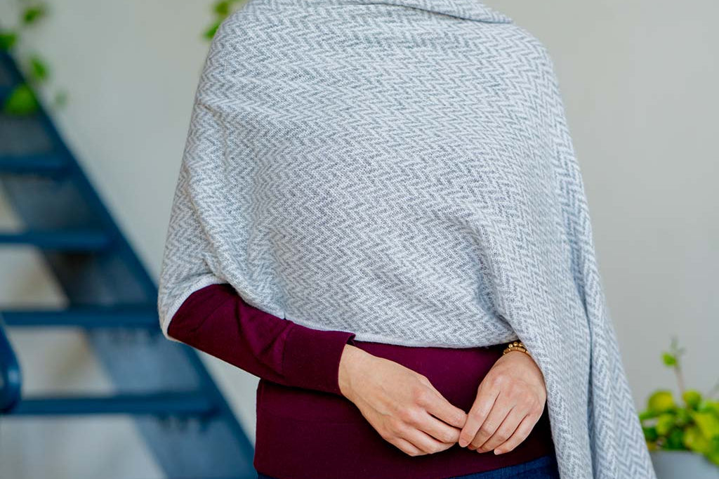 Model Wearing the Alpine Cashmere Herringbone Travel Wrap in Birch Gray and Ivory