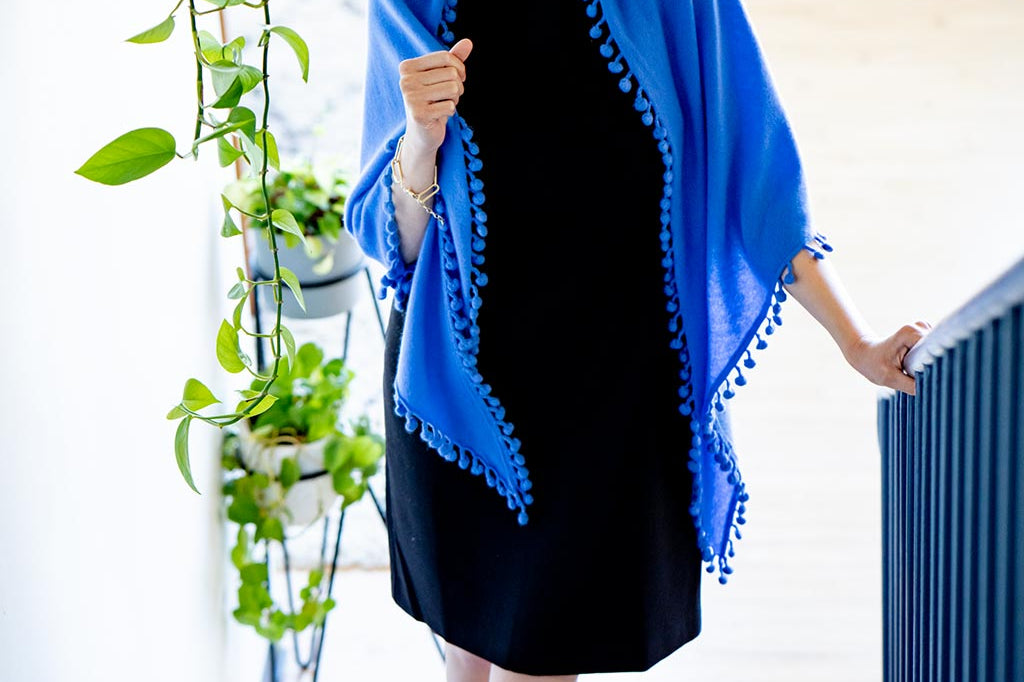 Model Wearing Alpine Cashmere Pom-Pom Triangle Wrap in Cornflower Blue