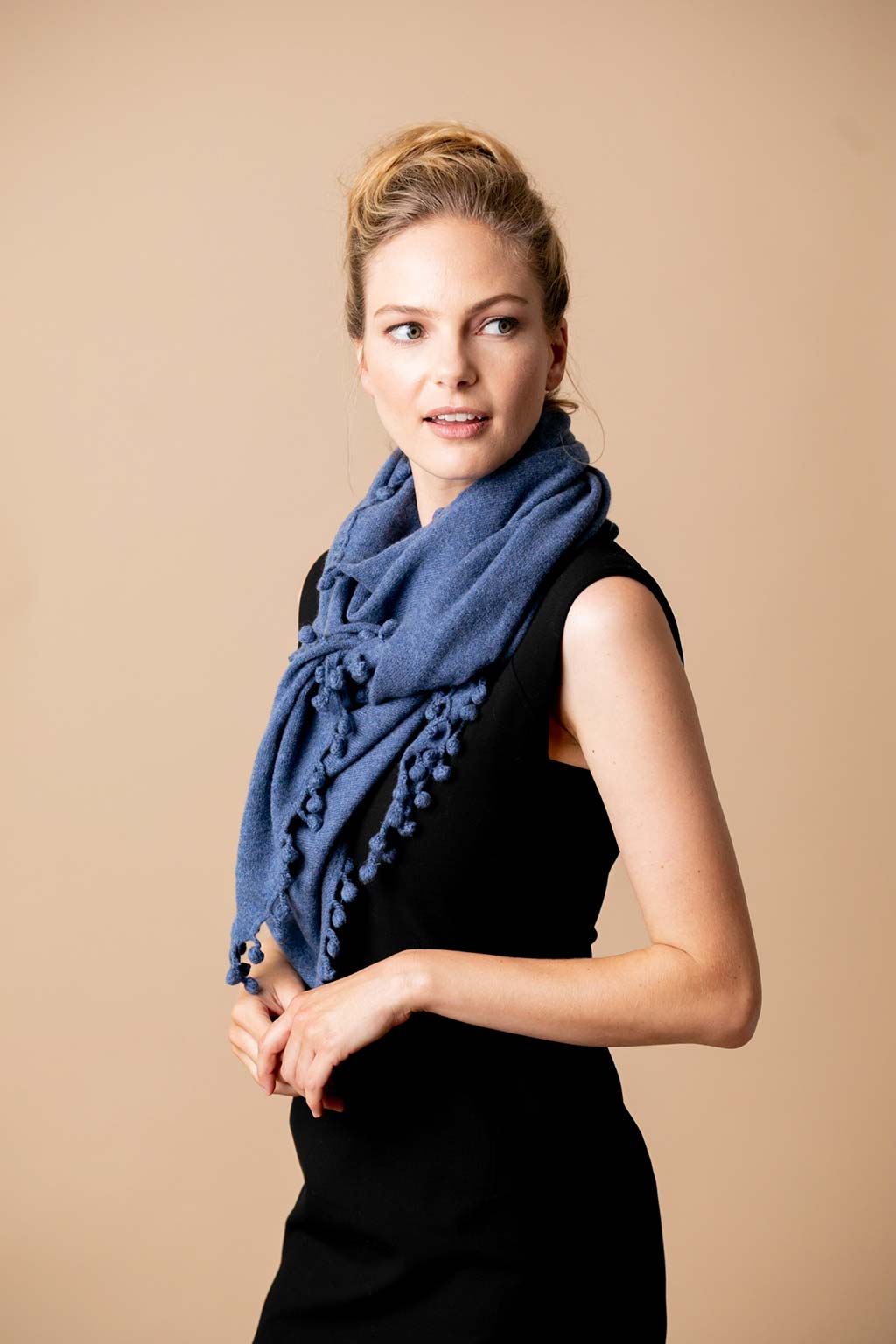 Model Wearing Alpine Cashmere Pom-Pom Triangle Wrap in Denim Blue