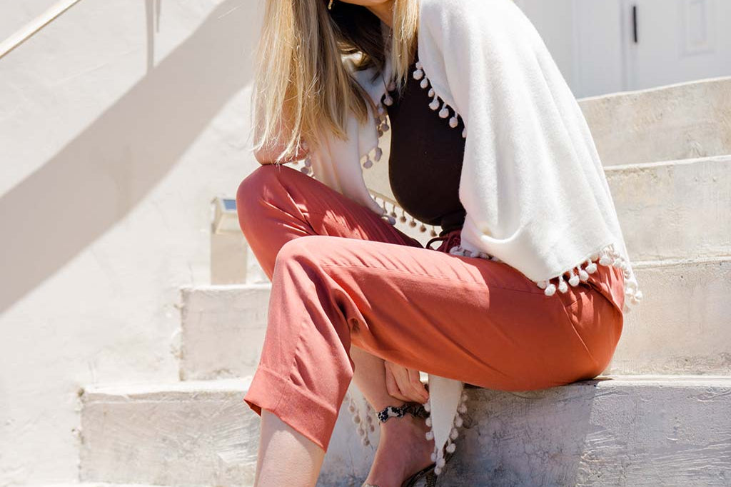 Model Wearing Alpine Cashmere Pom-Pom Triangle Wrap in Ivory