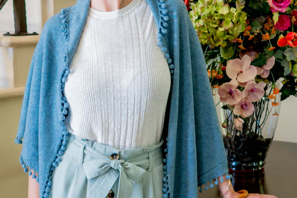 Model Wearing Alpine Cashmere Pom-Pom Triangle Wrap in Stonewash Blue