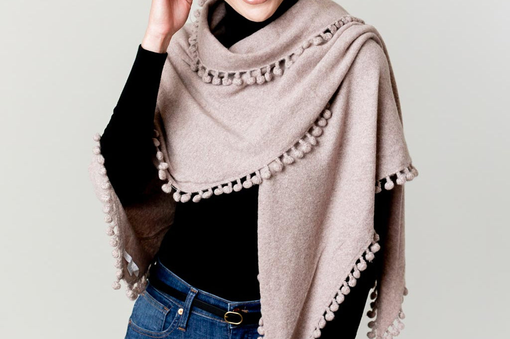 Model Wearing Alpine Cashmere Pom-Pom Triangle Wrap in Wheat